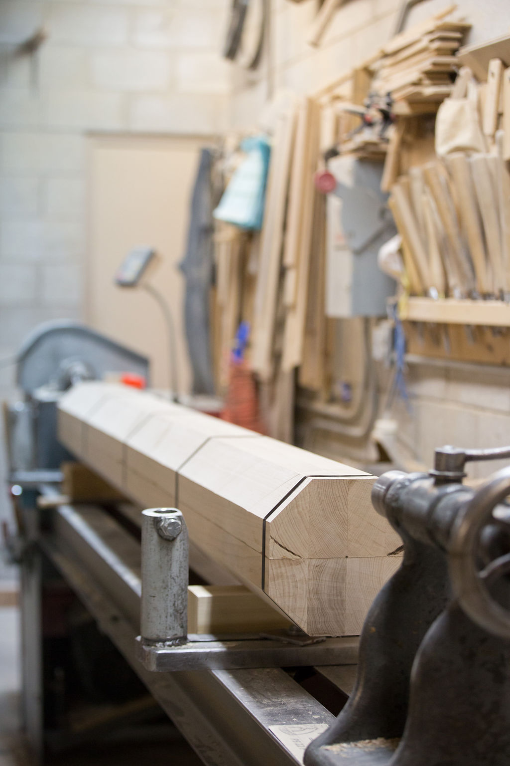 A woodturner shaping a large newel post on a hand lathe in the A&D shop