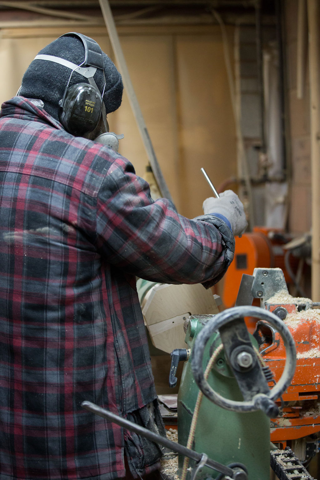 A turner sanding a spindle on the lathe
